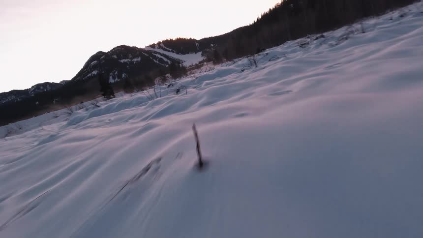 FPV drone shot rushing over a snowy landscape with trees and rivers