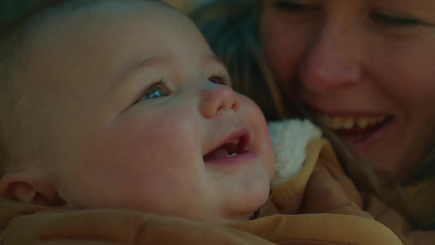 A close up of mothers face while holding her baby daughter as they laugh and smile