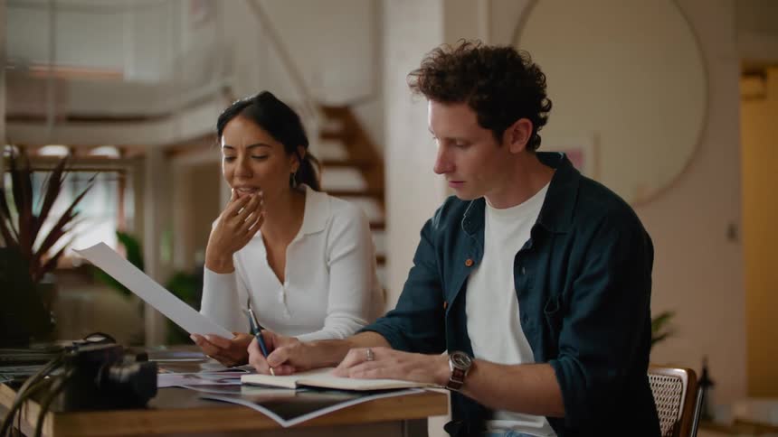 Man and woman in creative office space sitting at desk collaborating and discussing design