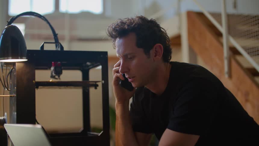 Man in black shirt talks on smartphone at the office