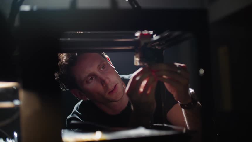 A young white man is indoors and fixing something