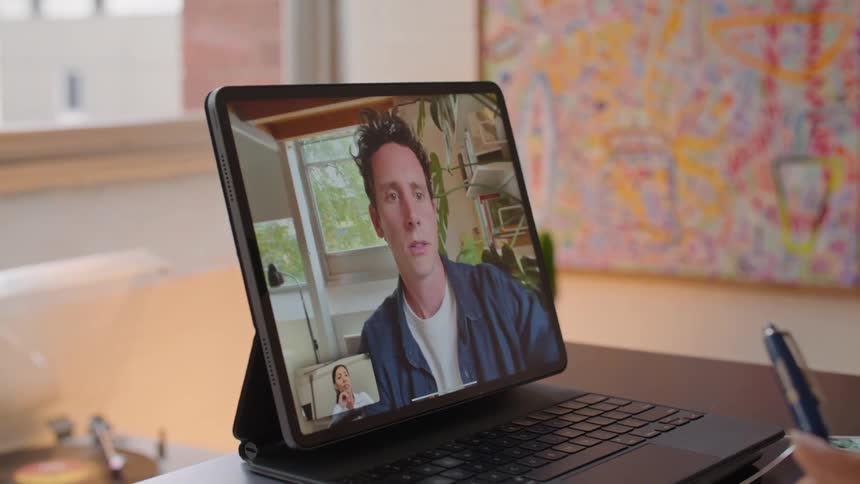 A man and woman talking on a tablet to each other