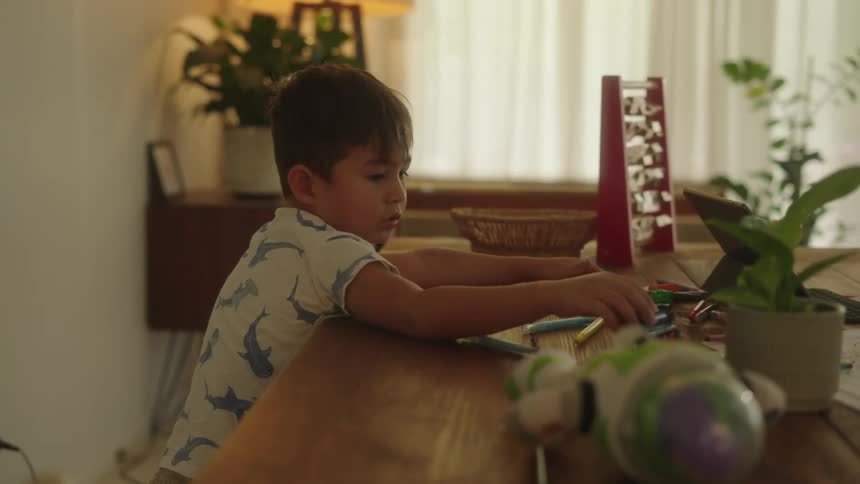 Toddler boy at home sitting at dining table alone playing with toys during the day