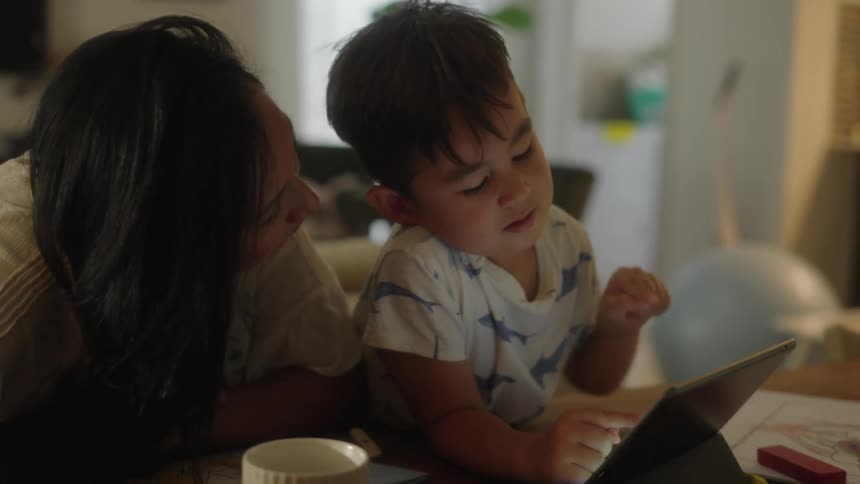 Mother and son sitting on the living room browsing on a laptop at home
