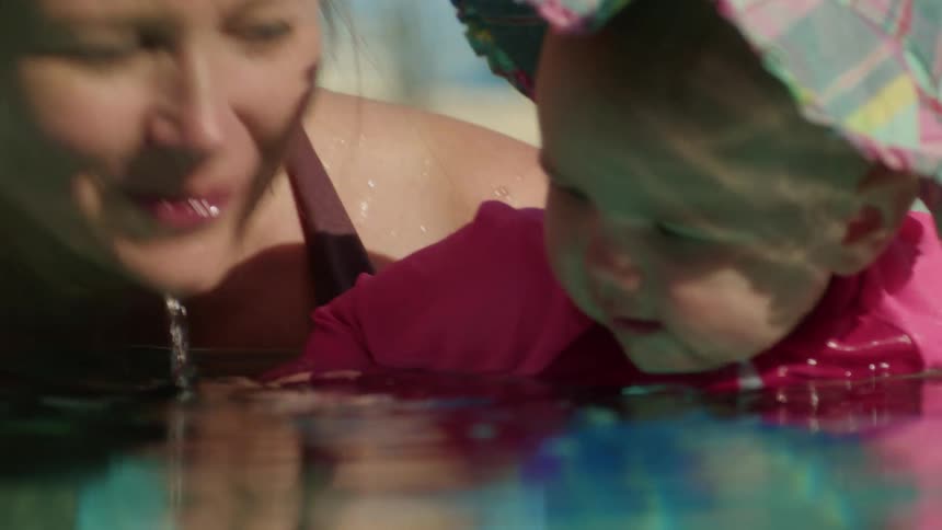 Mother and baby are in the pool outdoors in the day time