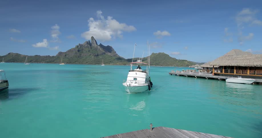 A boat approaches a dock in a bright blue bay