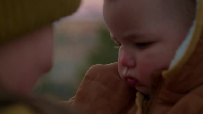 A close up of a babys face up close next to her mothers face both with rosy red cheeks