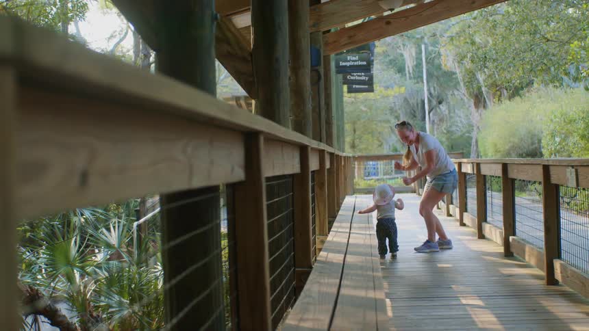A woman dances with her baby on a pedestrian bridge in a park