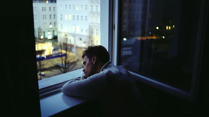 Bored man look out the window at apartment building