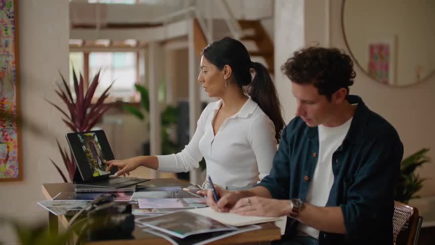 A man and woman organize digitized photos on a laptop