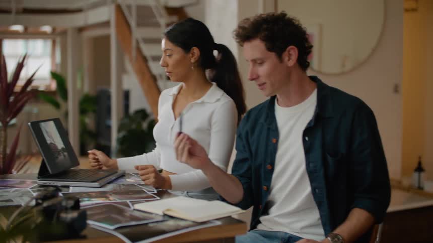 Man and woman sitting at table make video call on tablet