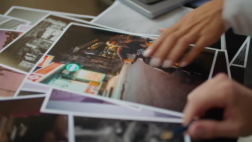 A close up of peoples hands as they point to picture on the table in front of them