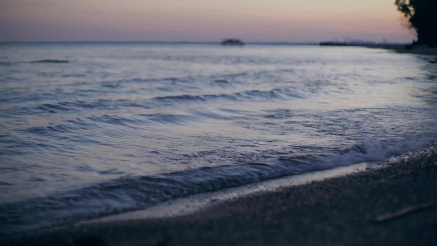 Waves roll onto beach under a red tinted sky