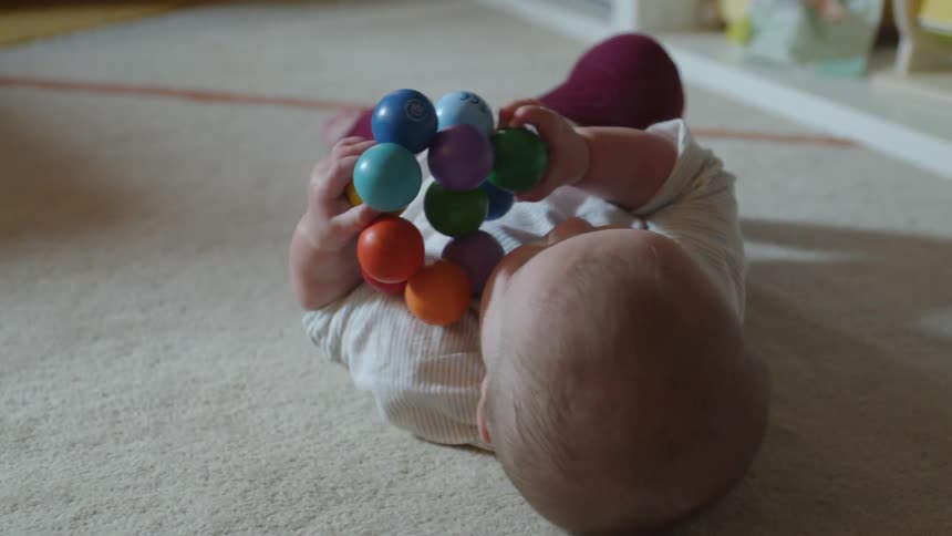 Baby plays with classic baby beads on the carpet