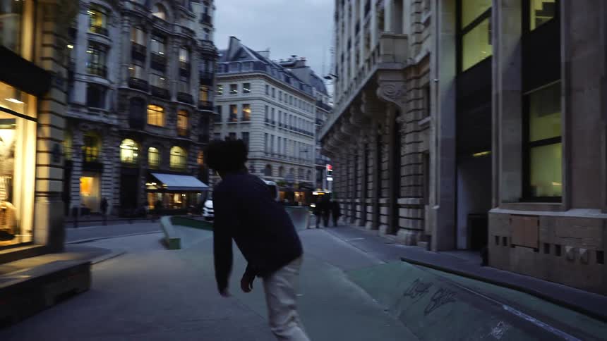 A teenager turns the city corner on his skateboard