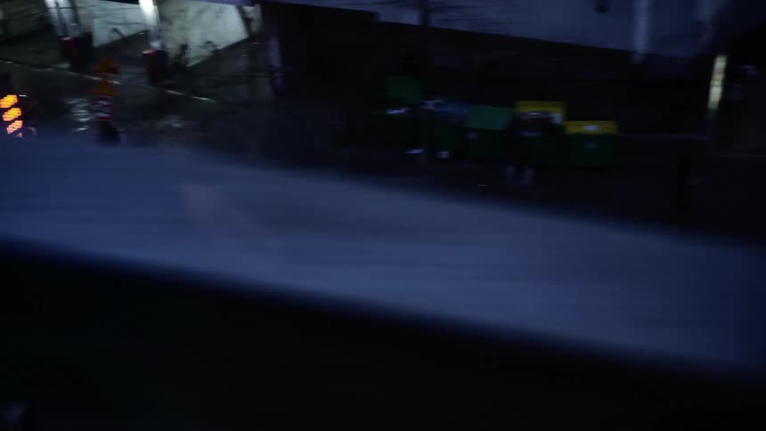 Vehicles move along city street paralleling bridge
