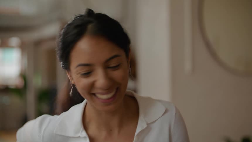 Woman with ponytail and white shirt and man with black shirt talk to each other laughing while working