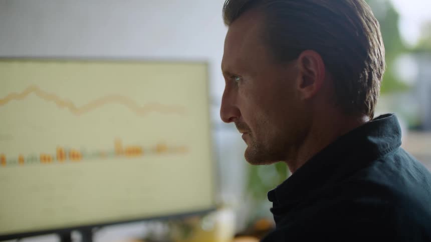A man is sitting at his computer desk in his office
