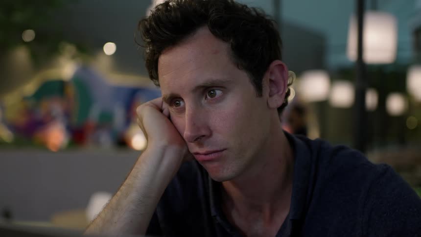 Man sitting alone with laptop at restaurant at nighttime in deep thought working late