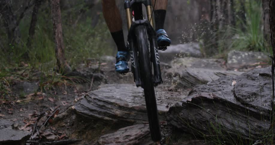 A person rides a bike down a rocky trail