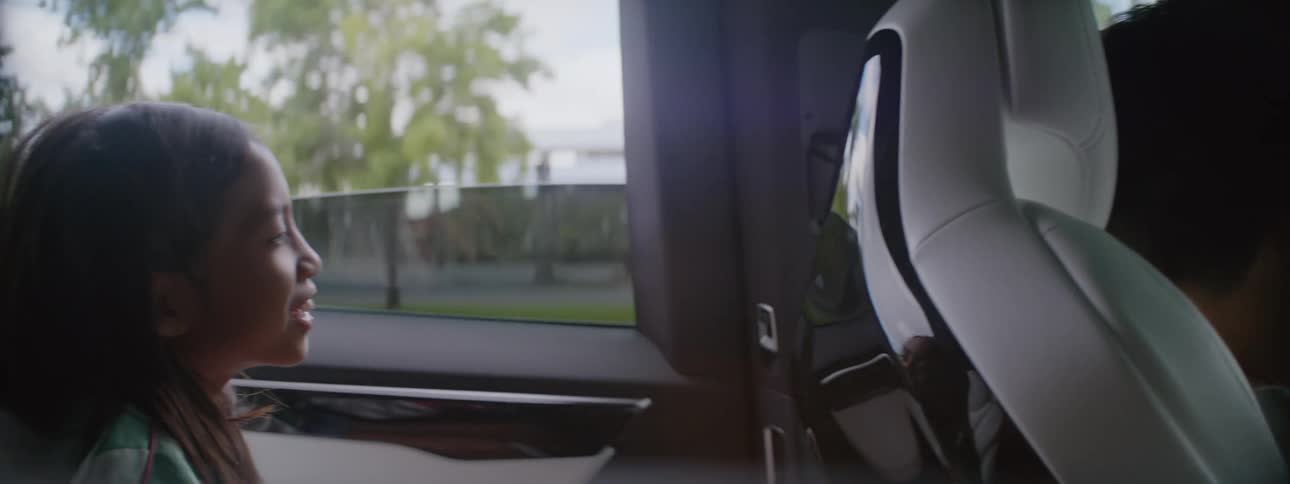 A woman driving a car talks with a girl sitting in the back seat