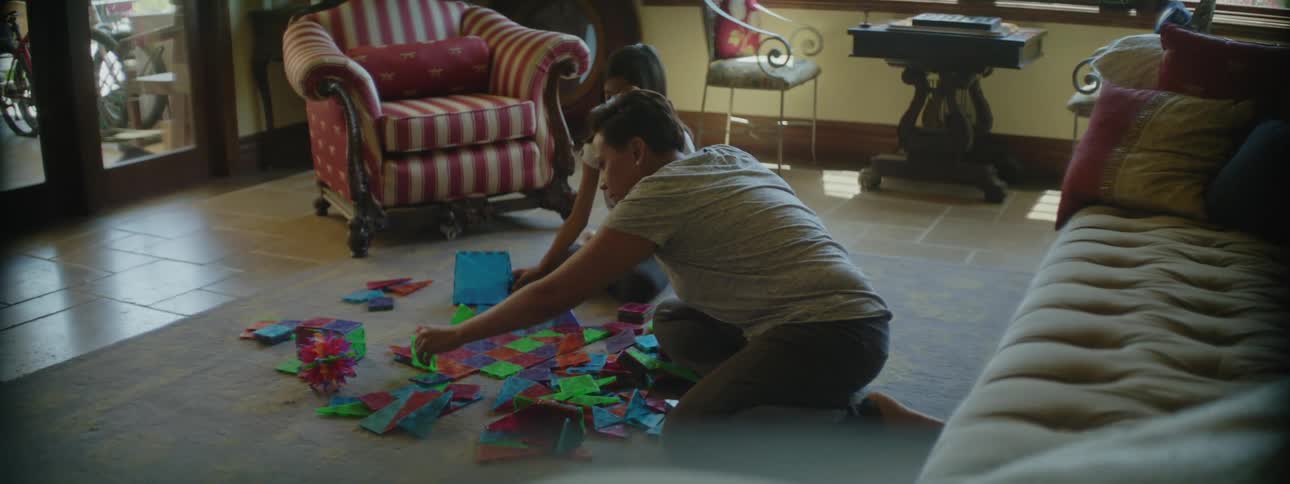 Mother and daughter assemble a puzzle in the living room floor