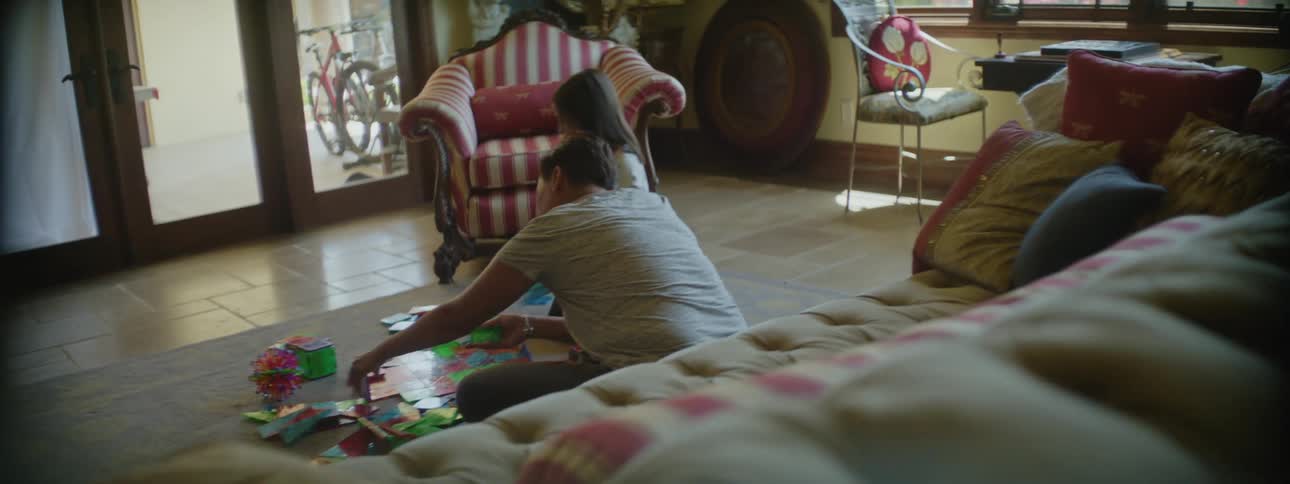 Mother and daughter sitting on the living room floor assembling a puzzle