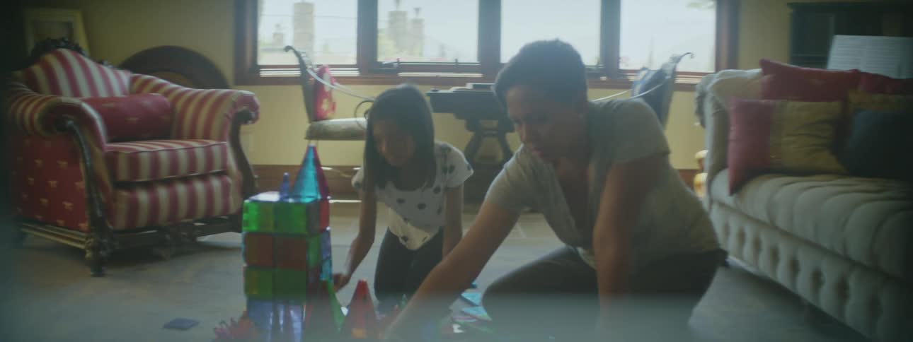Grandmother and granddaughter playing together on the floor with toys in the living room laughing and smiling
