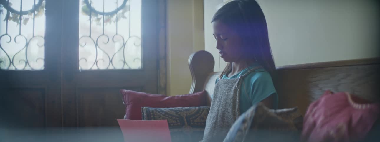 Young girl sitting on bench in foyer at home reading probably home schooling