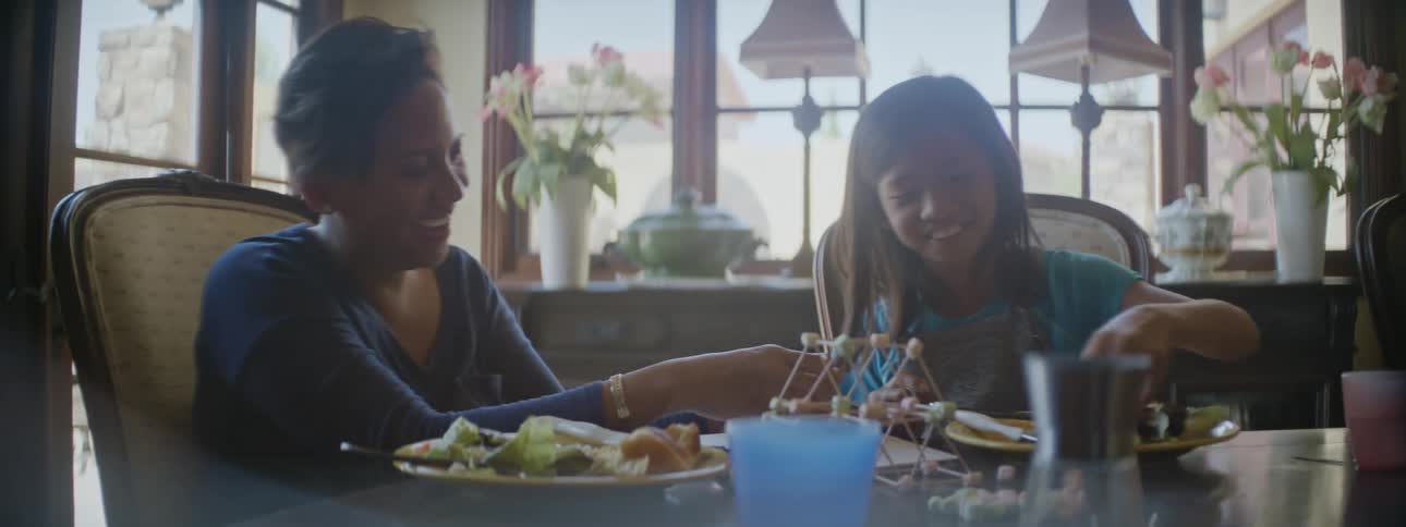 Mother and daughter smile while talking over lunch in the dining table at home