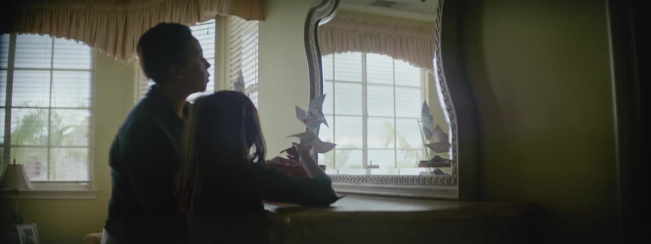 Mother and daughter stand in front of dresser mirrorand play with pinwheels