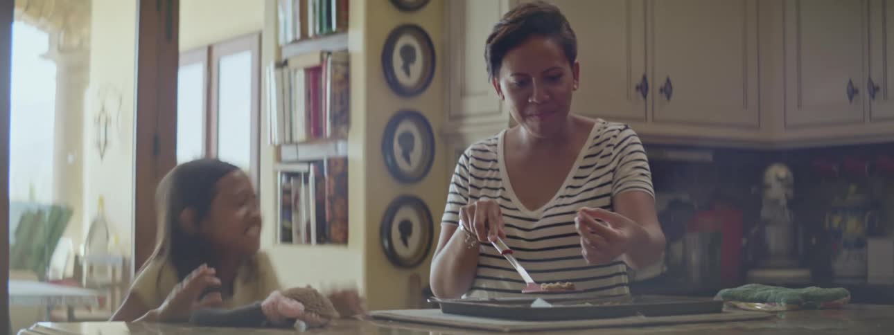 A grandmother and excited daughter have fun sampling fresh food at home in the kitchen