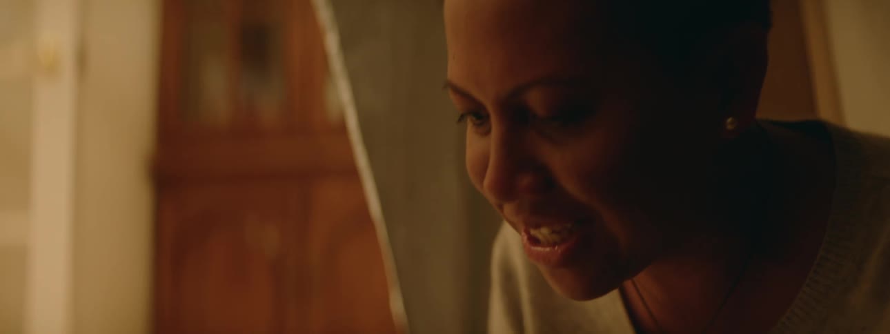 Woman laughs while talking to someon while sitting on the living room floor