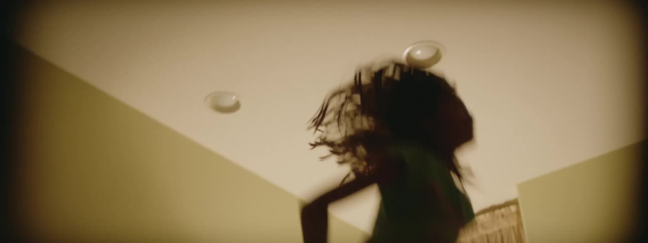 A young girl jumping up and down on her bed with a lamp on in the corner
