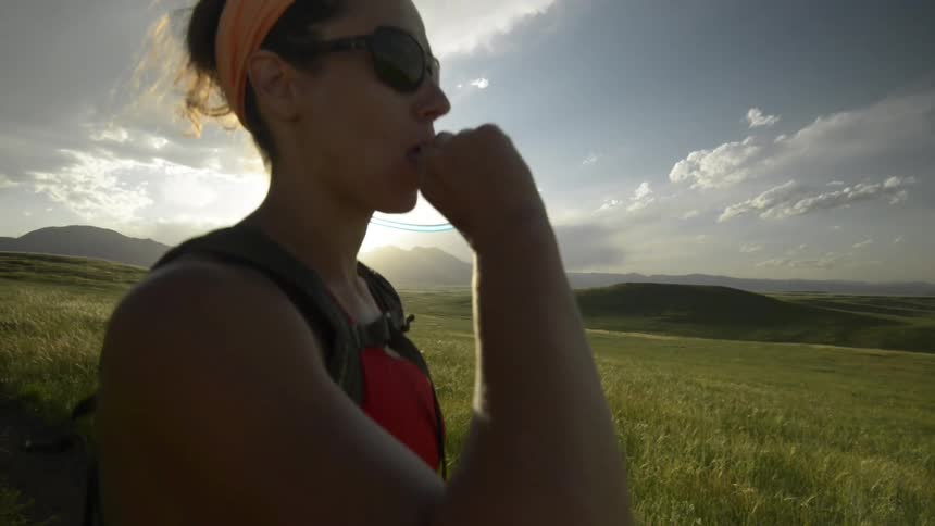 A woman drinks water from a hose in her backpack