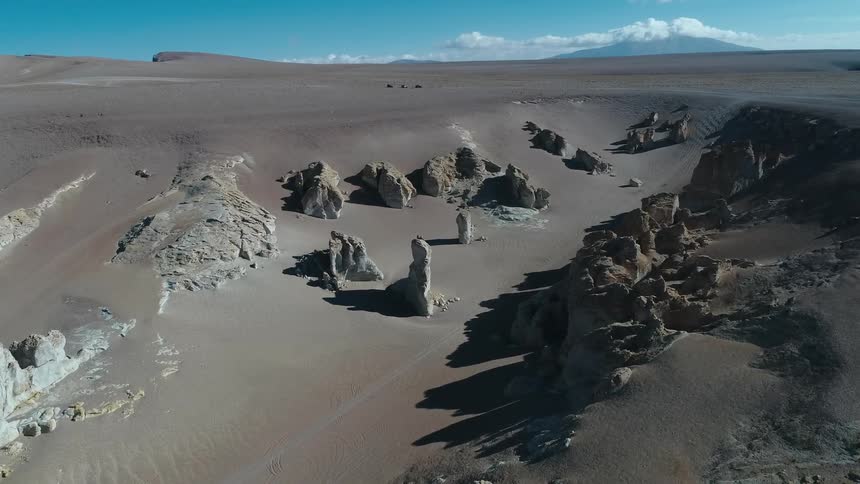 Rock outcroppings cast shadows onto desert spreading to misty mountain on the horizon