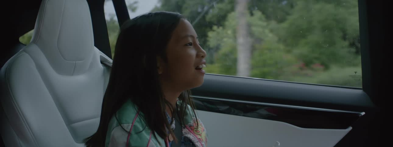 Happy girl talks while sitting on the back seat of a car driving through town