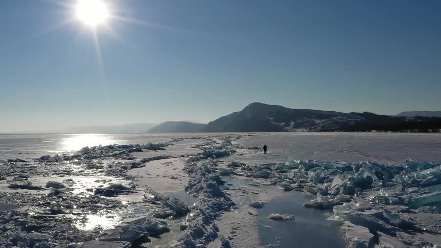 A person is walking over the iced shore