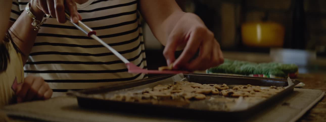 Mother and child are indoors and baking cookies