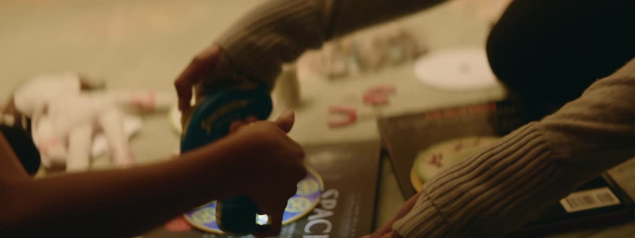 A close up of a womans face smiling and then showing her playing a game with someone else on the floor with her