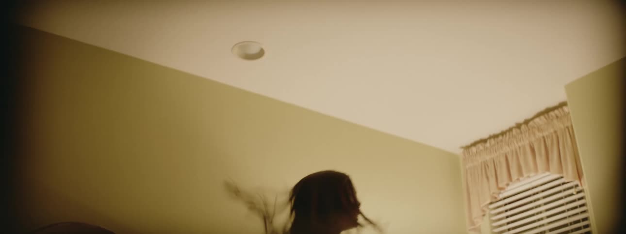 A young girl jumping on a bed as light reflects off the ceiling