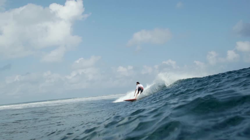 A surfer is riding a big wave as they bend down and disappear in the water
