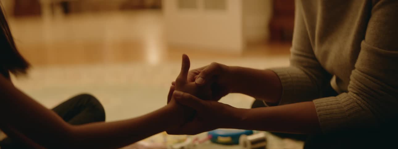 A mother and daughter play a game of thumb war inside their home