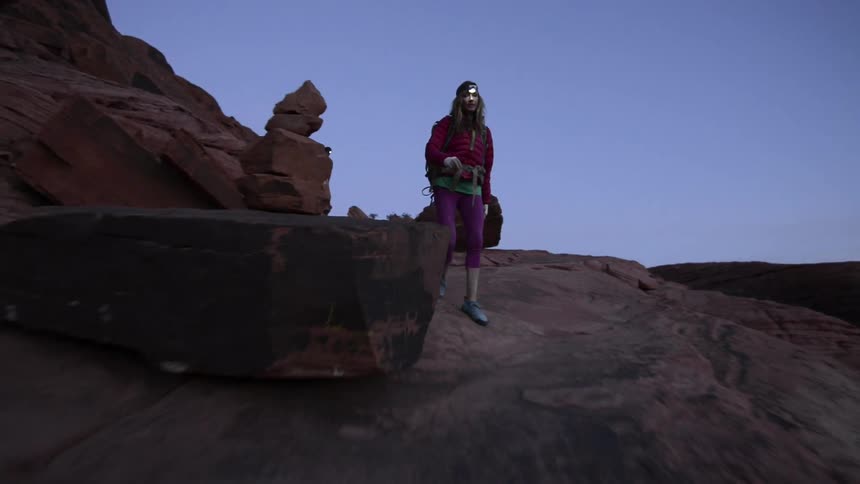Two mountaineers wearing colorful clothes walk near the ridges of a mountain at evening