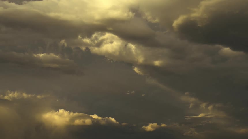 The sun shines on clouds moving across the sky and the light fades as the sun goes down