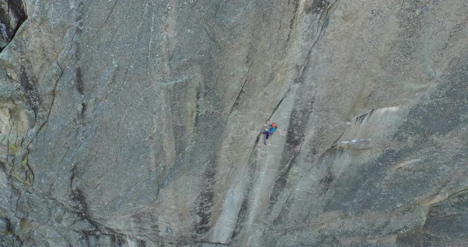 Rock climber perches on cliff overlooking forest