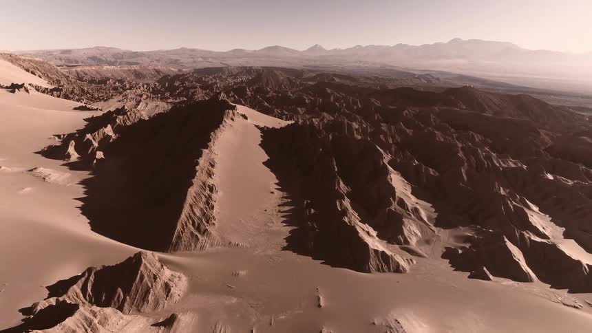 An aerial view of a snowy rocky mountains and valleys at dusk