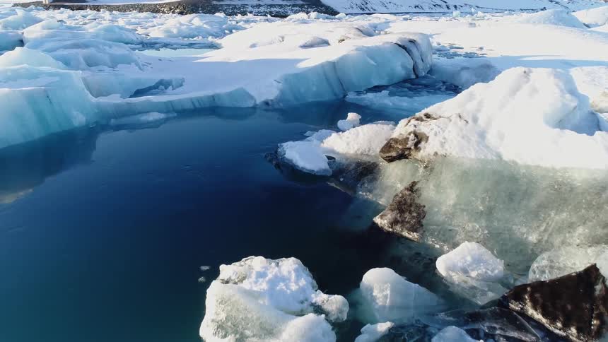 An aerial panorama of arctic ice chunks and snowy ground near the sea