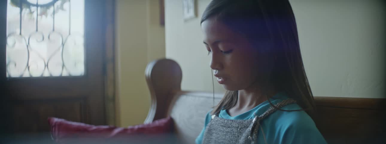 Girl sits in living room near front door looking downward