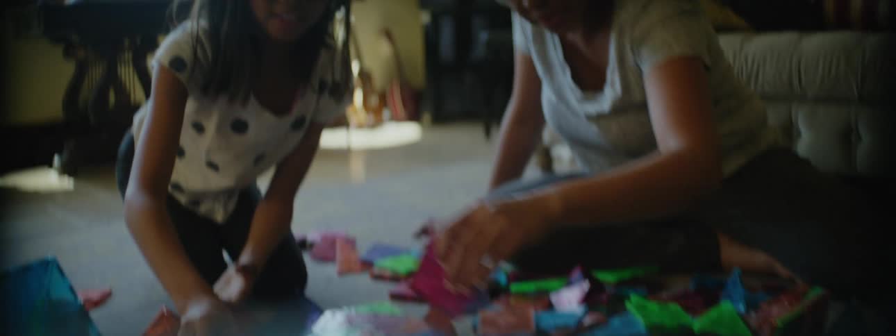Mother and daughter play with construction toys on floor of living room
